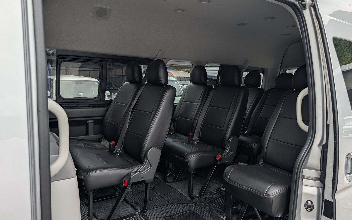 ハイエースの車内。黒い座席が3列並ぶ